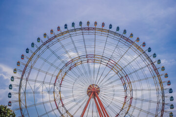 Fototapeta premium A ferris wheel with colorful cabins at a local fun fair
