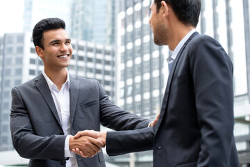 Young handsome Indian businessman make a handshake with partner in the city