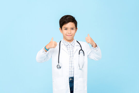 Handsome little kid doctor smiling and giving thumbs up isolated on light blue background