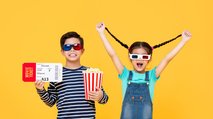 Adorable boy and girl having fun watching movies together on isolated colorful yellow background