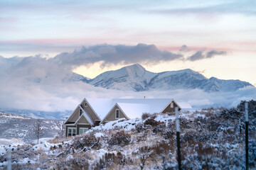 Snow covered Utah Valley with home amid hills and mountain under cloudy sky