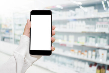Hand holding mobile smartphone in drug store to compare price of medicine