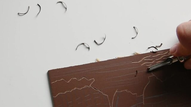 Slow motion view of linoleum carving with metal carving tool.