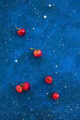 Some homegrown summer ripe cherry on the trendy phantom blue cosmoc concrete background. Minimal style. Free copy space for text. Close up macro shoot. Top view pattern