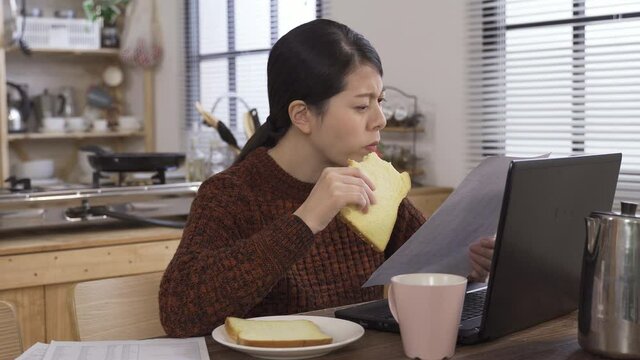 daytime chinese housewife having brunch is looking her bill. asian lady reading credit card check sheet feels something wrong with the charge and frowns with a doubtful look.