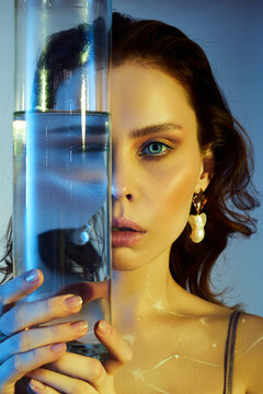 Beauty Portrait Of A Woman With A Large Glass Near Her Face. Distortion And Refraction Of Reflection Through Water