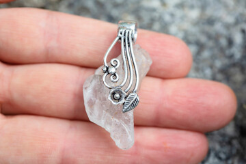 Natural crystal quartz gemstone with silver decoration pendant on female hand