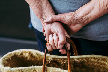 Mains d'une femme âgée tenant un panier en osier