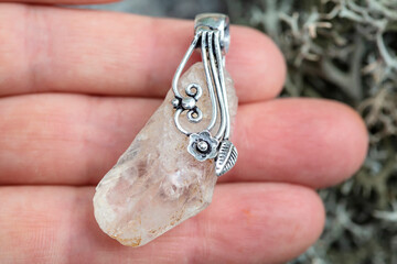 Natural crystal quartz gemstone with silver decoration pendant on female hand