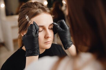 Correction and tinting eyebrows, master applies thread to woman on brow