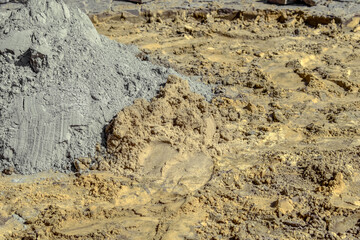 A gray pile of dry cement poured over yellow sand. Texture of building materials close-up, background with copy space