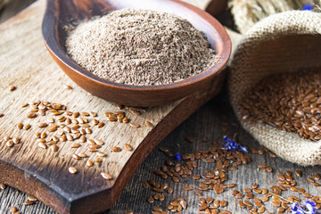 Flax seeds or flaxseed are in the bag on old boards near the chopped flax seed in a wooden spoon.