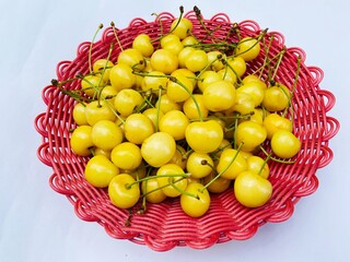 Yellow cherries in red basket on white background 