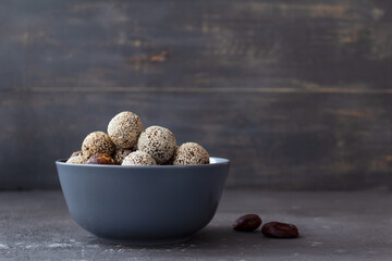 Homemade energy balls in a bowl on a gray background with place for text. Healthy snack. Proper nutrition from dates and nuts.