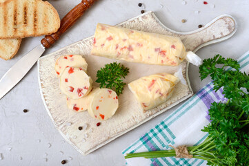 Portions of Herb Butter with pieces of sweet pepper for sandwiches and steaks sliced on a wooden board. Homemade italian food. The top view