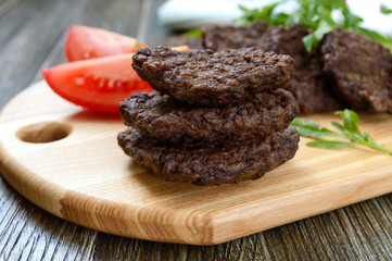 Tasty homemade liver cutlets stacked on a wooden board. Selective focus