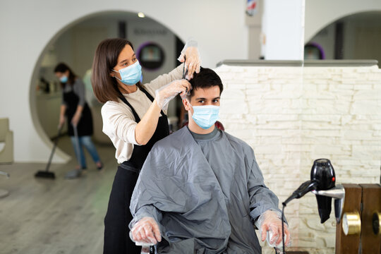 Client In Mask During Hair Cut By Professional Hairdresser In Mask