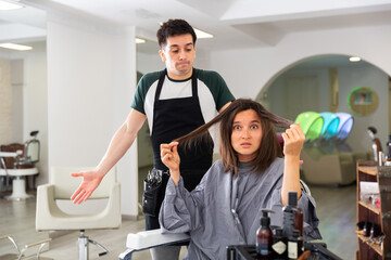 Displeased woman after haircut having conflict hairdresser