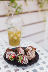 Handmade chocolate-covered strawberries on a plate in a summer cafe