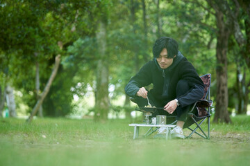 一人キャンプで料理をする若い日本人の男性