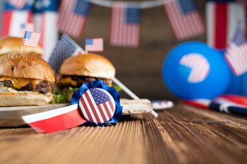 Fourth of July celebration. American flag and decorations. Burgers on rustic wooden table.