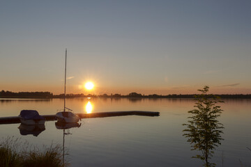 Fototapeta na wymiar Sailing boats at the landing stage at sunset on the lake shore