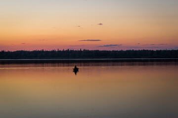 Fishermen in a rowing boat on the lake at sunset