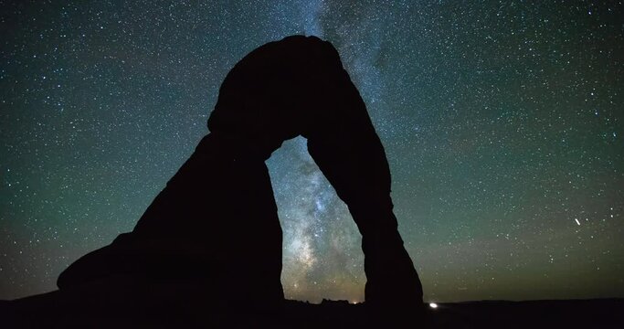 Time lapse shot of silhouette Delicate Arch in desert against Milky Way at night - Arches National Park, Utah