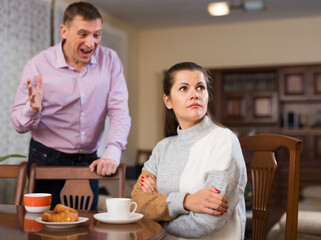 Irritated young spouses quarrelling in home interio