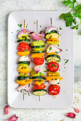 Grilled vegetable skewers on gray rectangular plate, top view. Vegan food concept.