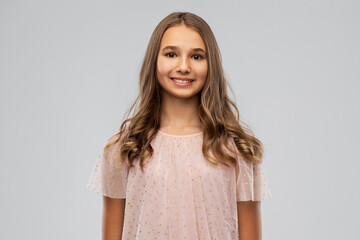 Obraz premium fashion and people concept - smiling young teenage girl in party dress over grey background