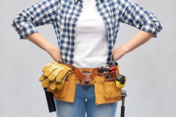 repair, construction and building concept - woman or builder with working tools on belt over grey background