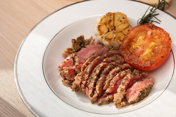 Grilled beef fillet in the white dish with herb tomato and garlic, daylight concept