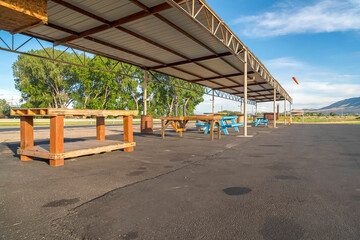 Tables and benches under flat corrugated metal roof of a pavilion at a park