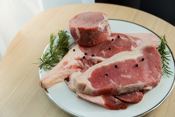 Mix of raw beefsteak tomahawk rib-eye tenderloin and strip loin with herb on wooden background