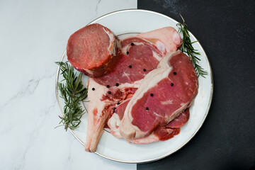 The mix of raw beefsteak tomahawk rib-eye tenderloin and strip loin with herb on marble background