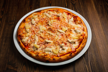 Ham, cheese, chicken meat and pineapple pizza, wooden background, low key