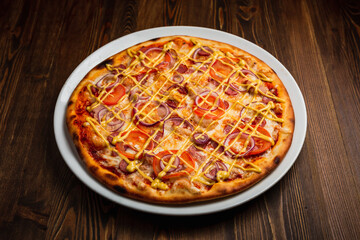Bacon, sausage, onion, tomato nourishing pizza with cheese sauce, wooden background, low key