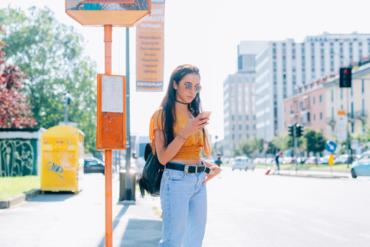 Young woman using smartphone while waiting at bus stop