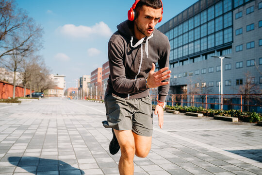 Young sportive man running listening music - Man jogger training in the city