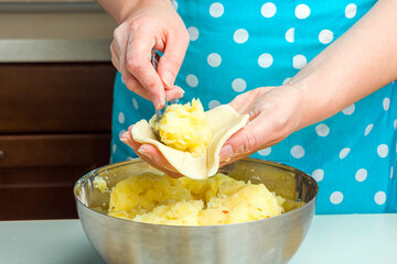 Cooking vegetarian dumplings with mashed potatoes (kreplach, jewish ravioli) in home kitchen. Step 9 female hands impose the potato filling in the  dough. Step by step instruction.