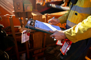 Site safety auditor supervisor verifying name of co workers on isolation lock permit board ensure...