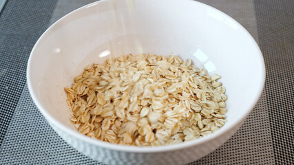 delicious yellow porridge cereals fall into white ceramic bowl on grey table in morning extreme close view