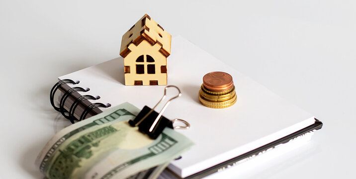 Mini wooden house and dollar banknote money on white background. Image for property real estate investment concept.