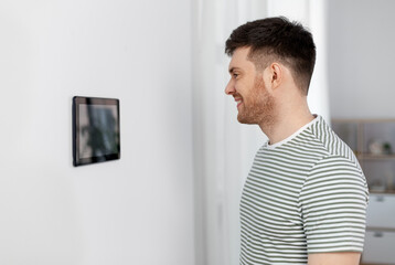 automation, internet of things and technology concept - happy smiling man looking at tablet pc computer at smart home