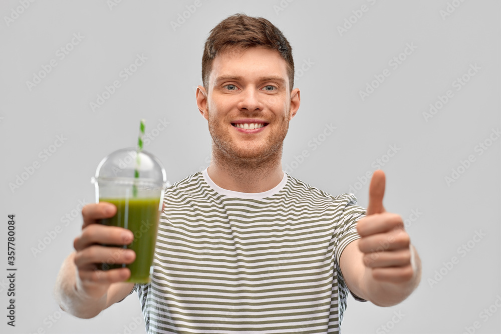 Wall mural healthy eating and people concept - happy smiling man holding green smoothie in disposable plastic c