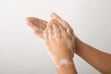 Fototapeta premium Child hands in soap bubbles against a grey wall. Concept of washing hands