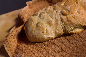 Homemade bread on a brown cloth towel on wooden cutting Board.
