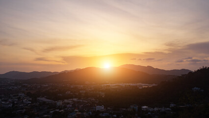 sunrise goes into sunset over hills surrounding valley with small town and forests in tropical country timelapse