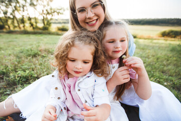 Blonde mother with two cute daughters are walking and having fun outdoors. Stylish, casual clothes.